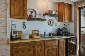 Eine Küche mit Holzausstattung, Spüle, Kaffeemaschine und diversen Küchenutensilien.
