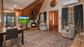 A cozy living room with a fireplace, a television, and a dining area.