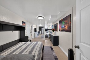 A hotel room with a bed, a desk, a chair, a small kitchenette, and a bathroom. - Midtown Reno Apartment | Workspace Near UNR (Reno)
