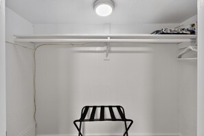 A white closet with a black metal rack, a white shelf, and a hanging rod. - Midtown Reno Apartment | Workspace Near UNR (Reno)