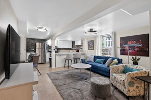 A modern living room with a blue sofa, a coffee table, and a flat-screen TV. - Mt Rose Retreat | Near Midtown & Downtown (Reno)