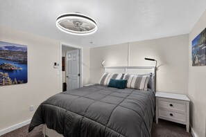 A bedroom with a bed, bedside tables, a ceiling fan, and wall art. - Mt Rose Retreat | Near Midtown & Downtown (Reno)