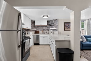 A modern kitchen with white cabinets, a black refrigerator, and a built-in oven. - Midtown Reno Apartment | Workspace Near UNR (Reno)