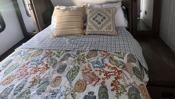 Une chambre à coucher avec un lit, des oreillers et une couvre-lit à motifs.