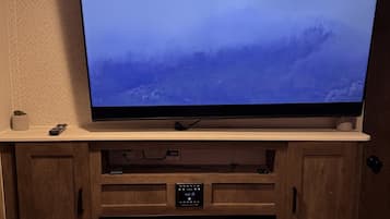 A television mounted on a wooden cabinet above a fireplace with a remote control on the cabinet.