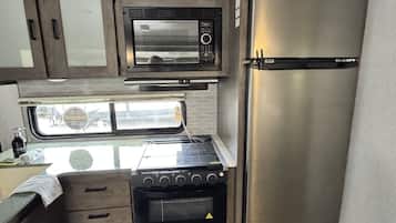 A compact kitchenette with a microwave, stove, and refrigerator.
