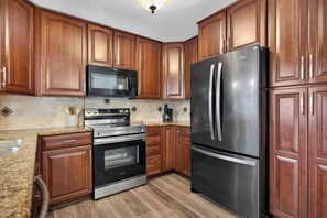 A kitchen with wooden cabinets, a stainless steel refrigerator, a microwave, and an oven. - The Oasis Private Pool +Gazebo 5 Minutes to the Beach! (Pompano Beach)