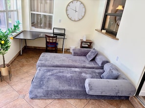 A room with a sofa, a desk, a chair, a clock, and a window. - The Oasis Private Pool +Gazebo 5 Minutes to the Beach! (Pompano Beach)