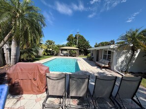A backyard with a swimming pool, covered chairs, and a covered table. - The Oasis Private Pool +Gazebo 5 Minutes to the Beach! (Pompano Beach)