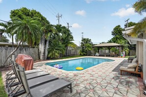 A backyard with a swimming pool, patio furniture, and a wooden fence. - The Oasis Private Pool +Gazebo 5 Minutes to the Beach! (Pompano Beach)