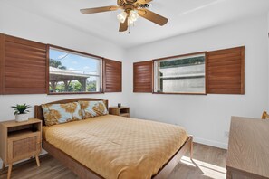 A bedroom with a bed, wooden headboard, two nightstands, a ceiling fan, and two windows with wooden shutters. - The Oasis Private Pool +Gazebo 5 Minutes to the Beach! (Pompano Beach)
