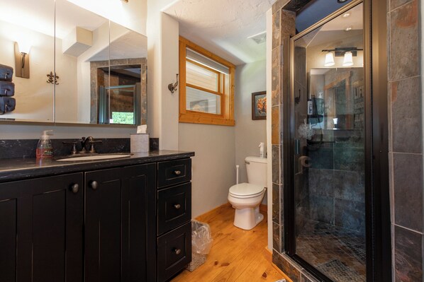 A modern bathroom with a black vanity, a glass shower enclosure, and a white toilet.