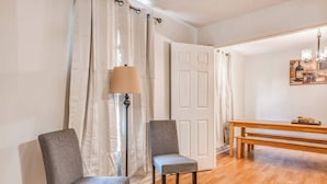 Een kamer met twee grijze stoelen, een vloerlamp, een houten bank en een deur.