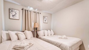 Een hotelkamer met twee bedden, een lamp en kunstwerken aan de muur.