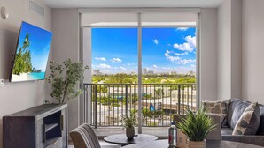 Un salon moderne avec un balcon, un téléviseur à écran plat, une table à manger et un canapé.