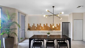 Une cuisine moderne avec un revêtement mural en bois, un coin repas doté d’une table et de chaises en bois foncé, et un luminaire suspendu au plafond.
