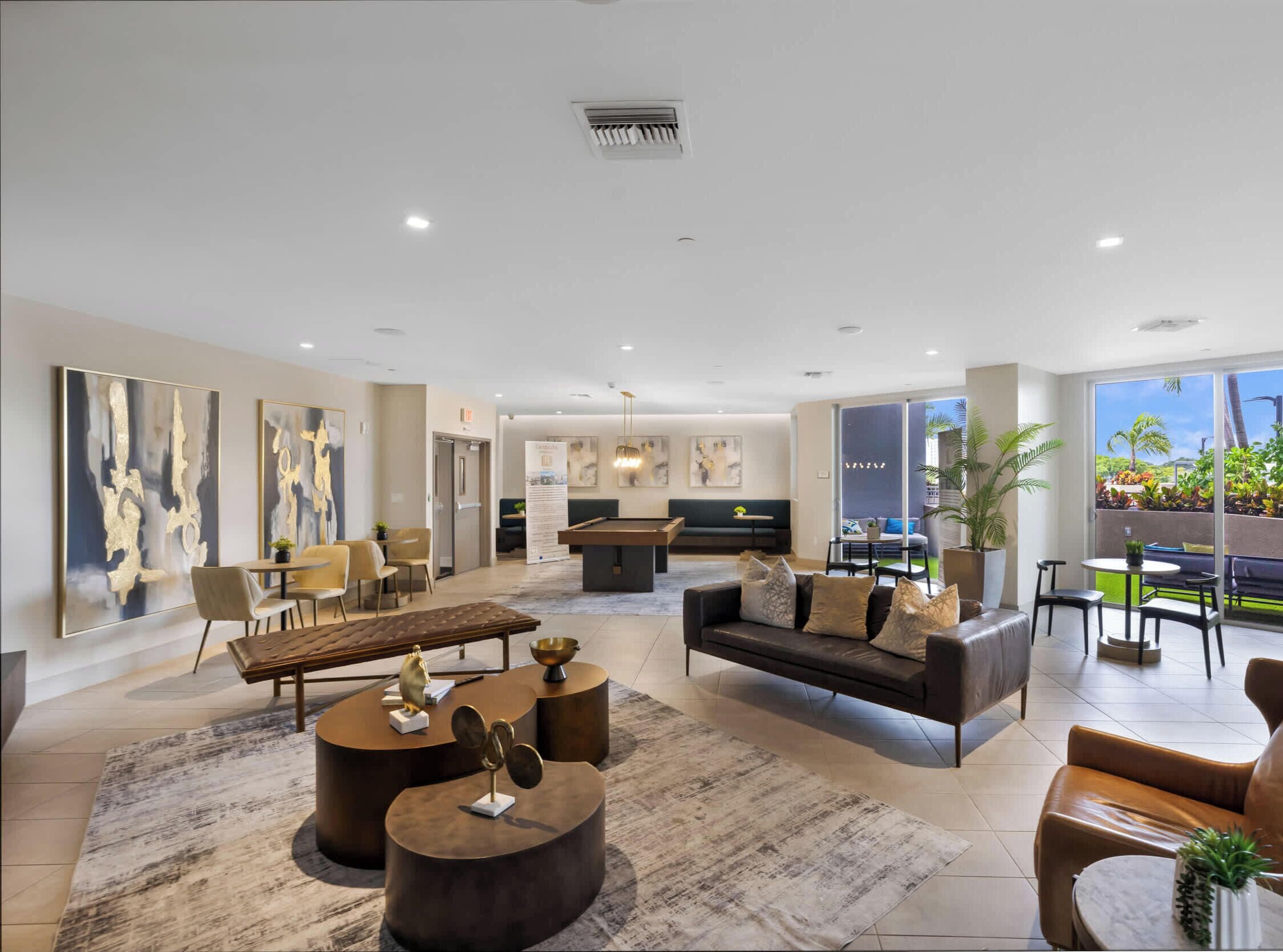 A spacious living area with a pool table, comfortable seating, and a view of the outdoors.