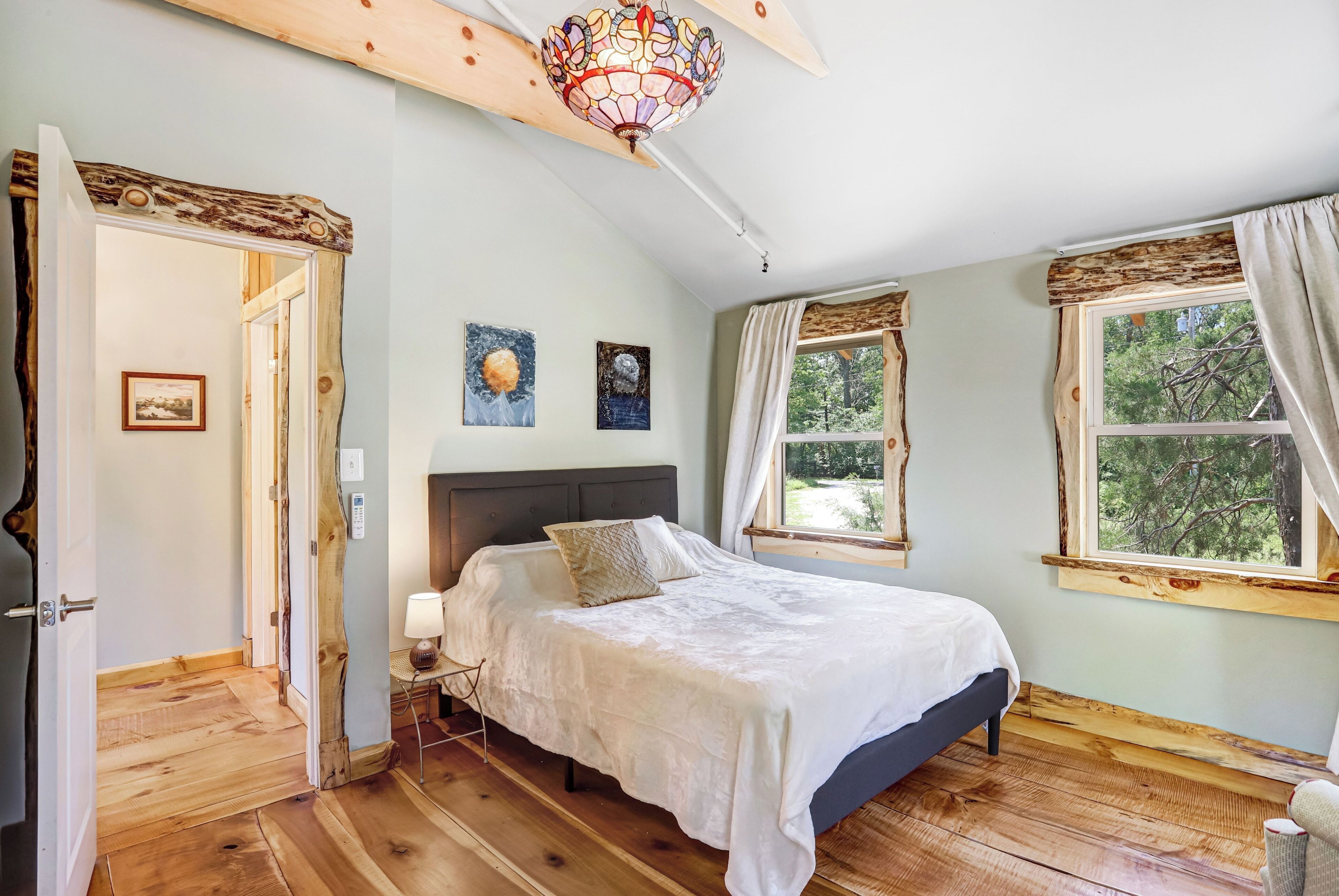 Un dormitorio con cama, mesita de noche, lámpara, lámpara de techo y ventana con cortinas.