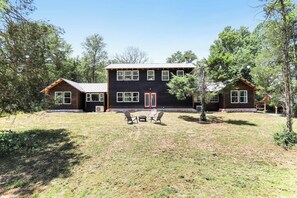 A two-story log cabin with a front porch, a covered patio, and a small outdoor seating area.