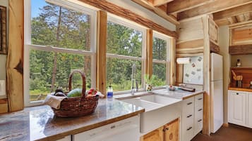 A kitchen with large windows, a sink, and a refrigerator.
