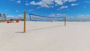 Ein Beachvolleyballnetz an einem sandigen Strand bei blauem Himmel.