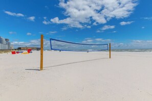 A beach volleyball net on a sandy beach with a clear sky. - San Carlos 1208 | Beach Front (Gulf Shores)