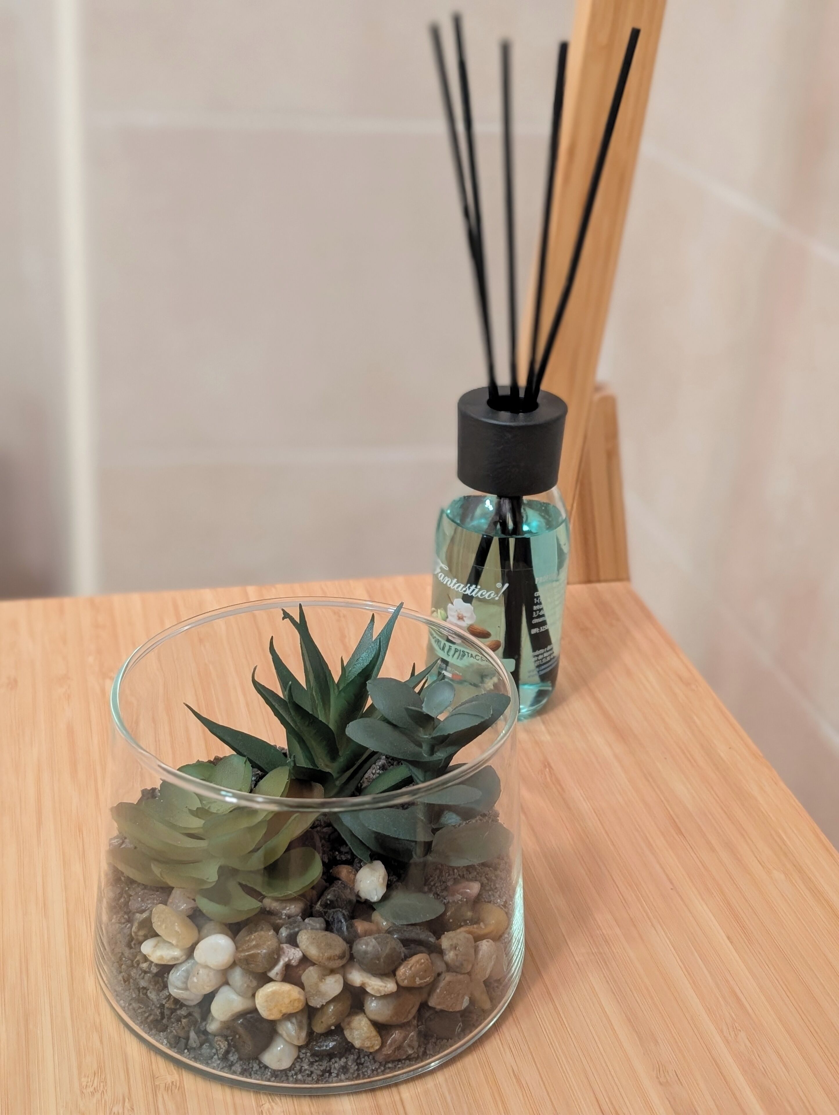 Un terrario de vidrio con una suculenta, piedras y una superficie de madera.