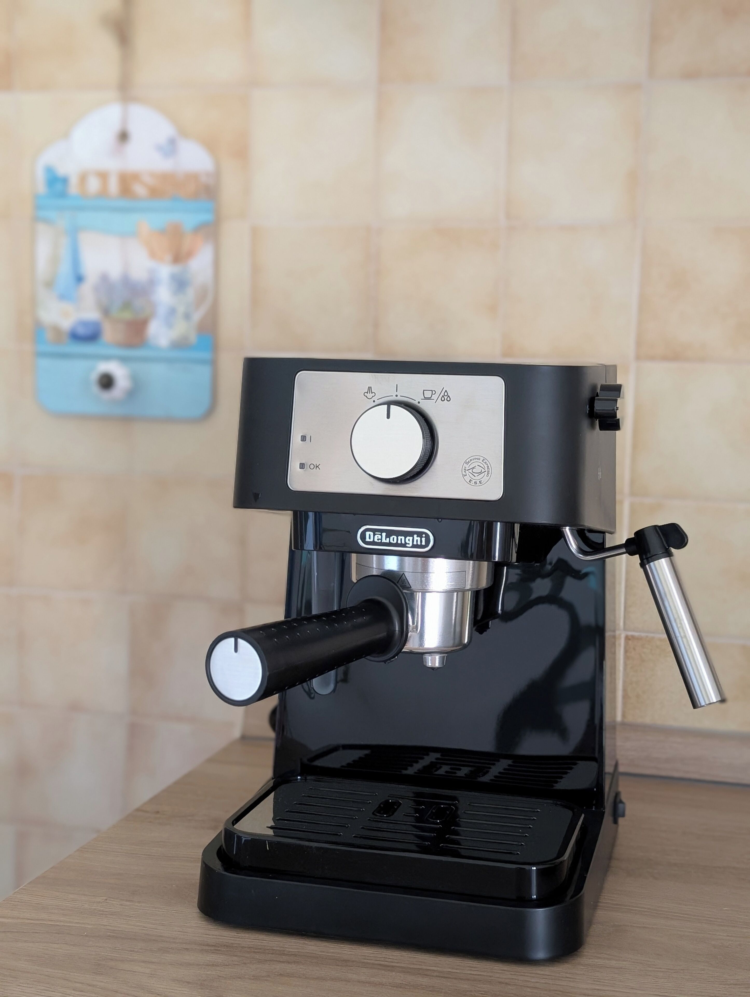A black coffee machine with a digital display, a steam wand, and a portafilter on a countertop.