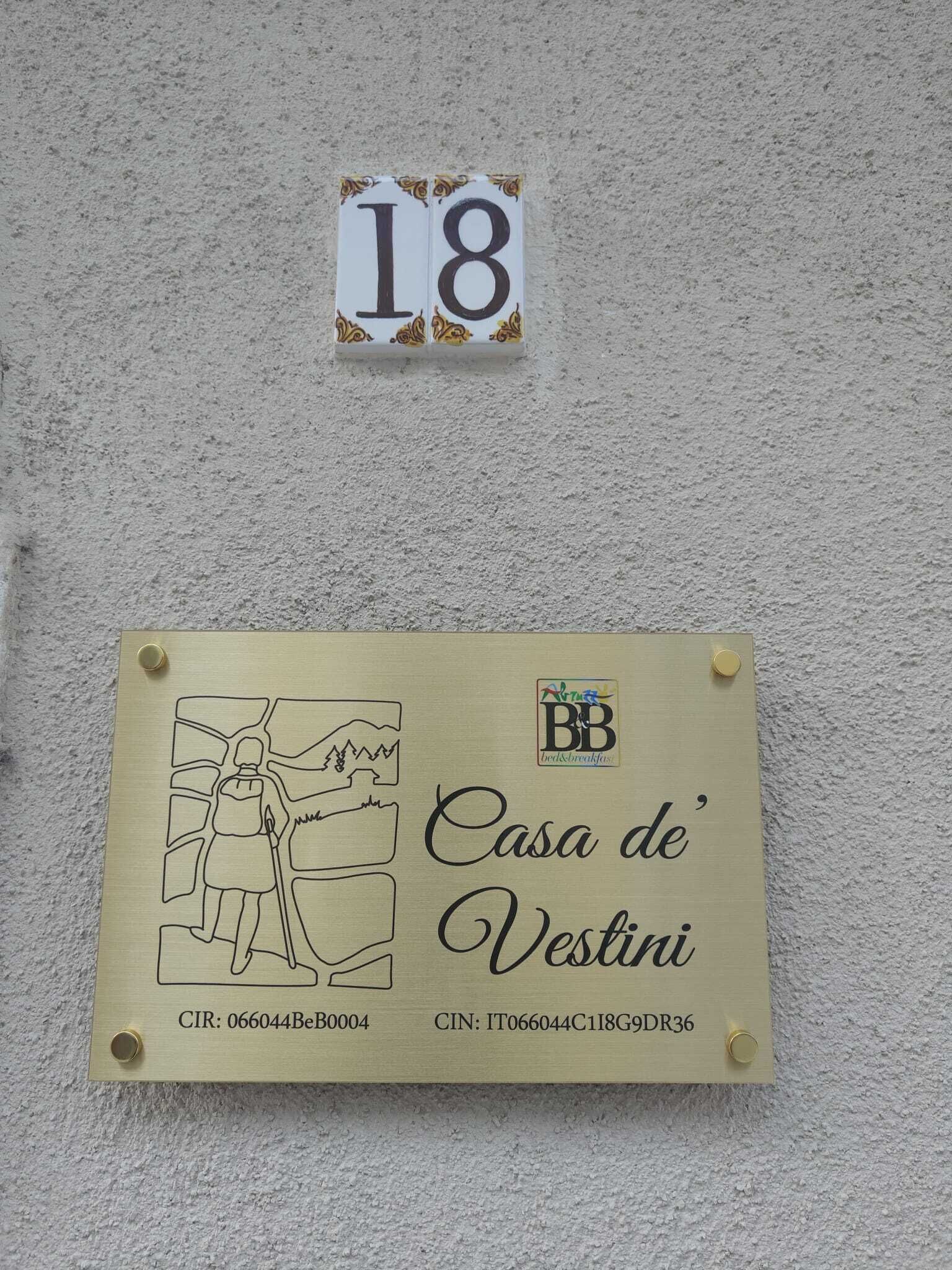Une plaque portant le numéro de maison 18 et une plaque nominative pour « Casa de’ Vestini », avec un logo et les coordonnées.