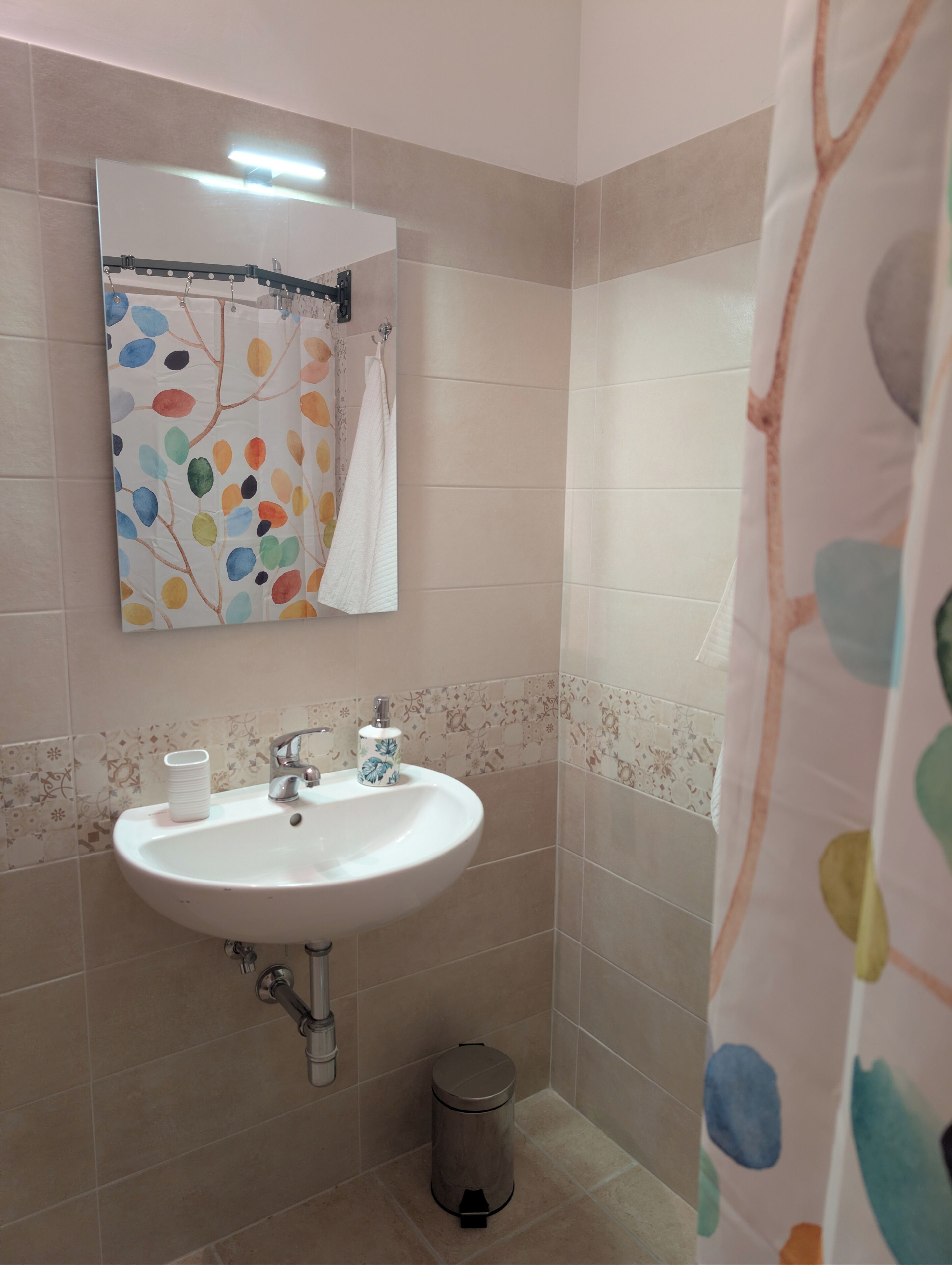 Une salle de bain avec un lavabo blanc, un miroir et des toilettes.
