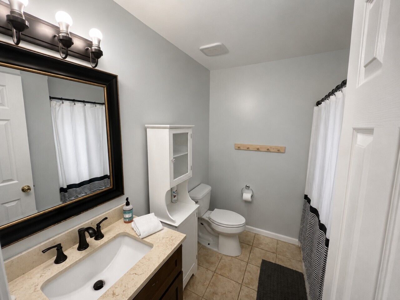 Une salle de bain équipée d’un lavabo, d’un miroir, de toilettes et d’un rideau de douche.