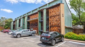 A multi-story building with a parking lot in front, featuring a mix of modern and rustic architectural elements. - Walk to Zilker & Barton Springs / Old Austin Charm / Private Patio & Parking (Austin)