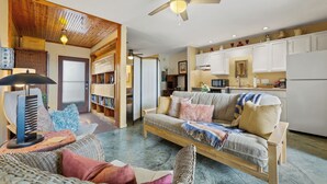 A living room with a sofa, a chair, a ceiling fan, and a kitchen area with cabinets and appliances. - Walk to Zilker & Barton Springs / Old Austin Charm / Private Patio & Parking (Austin)