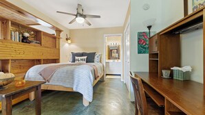 A bedroom with a bed, a wooden desk, a chair, a ceiling fan, and a bathroom visible through an open door. - Walk to Zilker & Barton Springs / Old Austin Charm / Private Patio & Parking (Austin)