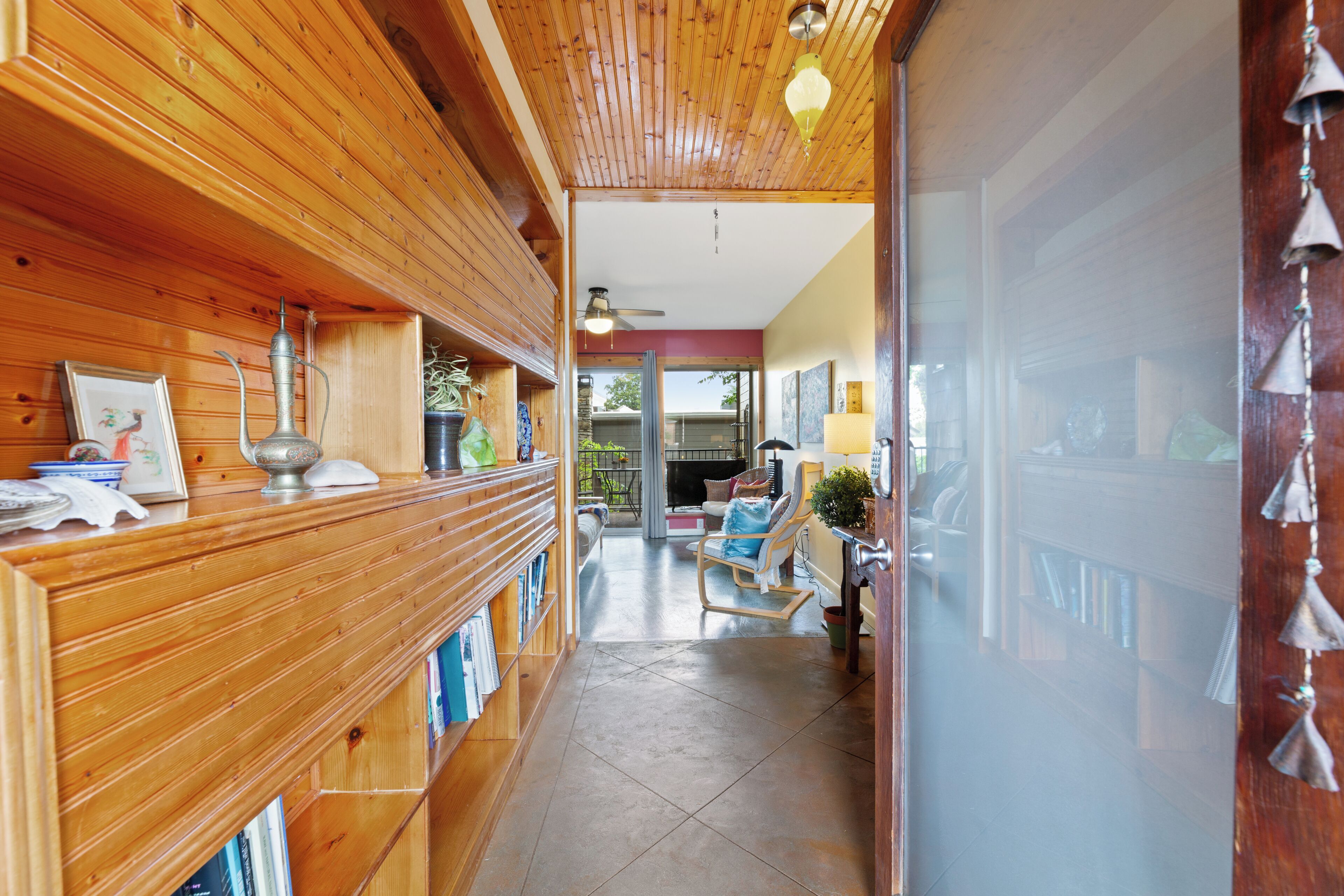 Un interior de madera con una recepción, estanterías y un área de descanso con una silla y una mesa.