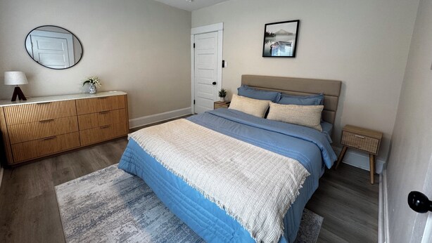 Ein Schlafzimmer mit einem Bett, einer Kommode, einem Deckenventilator, einem Spiegel und einem gerahmten Bild an der Wand.