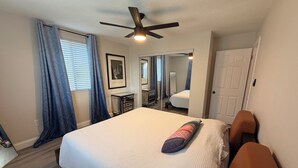 A bedroom with a bed, a ceiling fan, a bedside table, a mirror, and a door. - Peaceful Poolside Retreat Near Orlando Health.  Resort Style Amenities Workspace (Orlando)