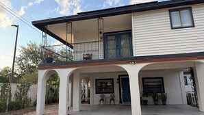 A two-story house with a covered porch, a balcony with a chair, and a blue door. - Peaceful Poolside Retreat Near Orlando Health.  Resort Style Amenities Workspace (Orlando)