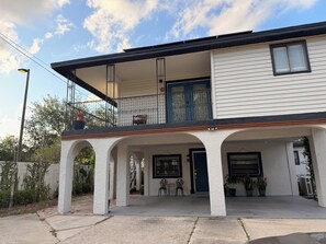 A two-story house with a covered porch, a balcony with a chair, and a blue door. - Peaceful Poolside Retreat Near Orlando Health.  Resort Style Amenities Workspace (Orlando)