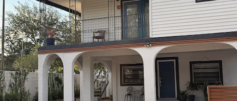 A two-story house with a balcony, a covered porch with columns, and a front door.