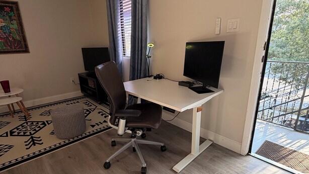 A room with a desk, chair, computer, and a view through a door. - Peaceful Poolside Retreat Near Orlando Health.  Resort Style Amenities Workspace (Orlando)