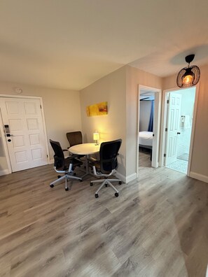 Een kamer met een ronde tafel, twee bureaustoelen, een lamp en een plafondarmatuur.