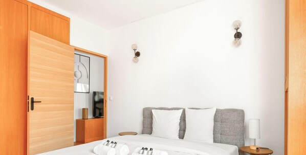 Ein Hotelzimmer mit einem Bett, einem Holzschrank, einem Spiegel, einer Wandleuchte und einem Nachttisch mit Lampe.