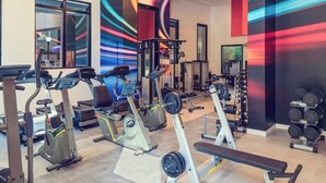 Ein Fitnessstudio mit Laufbändern, Hanteln und Trainingsbänken.