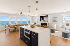 Une cuisine moderne dotée d’un grand îlot central, d’un coin repas et d’une cheminée.