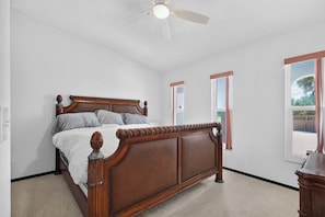 Una camera da letto con un letto di legno, una ventola a soffitto e una finestra vista.