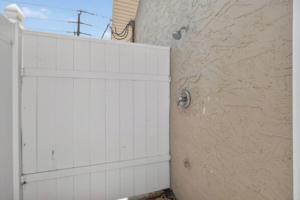 A white wooden gate, a textured beige wall, and a metal door handle. - Beautiful 4-bedroom beach front house in Ponce Inlet (Port Orange)