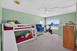 A room with bunk beds, a desk, an exercise bike, and a view of the beach. - Beautiful 4-bedroom beach front house in Ponce Inlet (Port Orange)