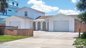 A residential property with a garage, a driveway, and a wooden fence. - Beautiful 4-bedroom beach front house in Ponce Inlet (Port Orange)