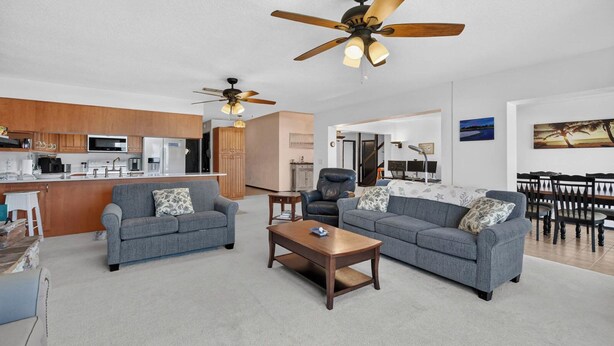 A modern living room with two grey sofas, a wooden coffee table, and a ceiling fan. - Beautiful 4-bedroom beach front house in Ponce Inlet (Port Orange)